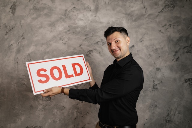 person holding a "sold" sign