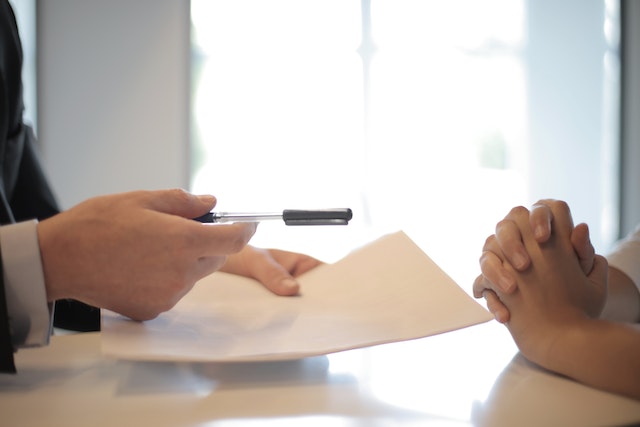 person handing over pen and contract