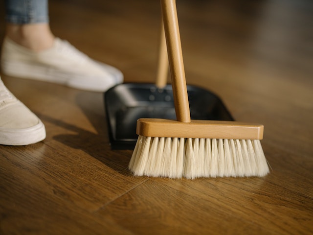 person sweeping wooden floor