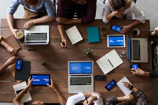 work team working around a wooden table on computers