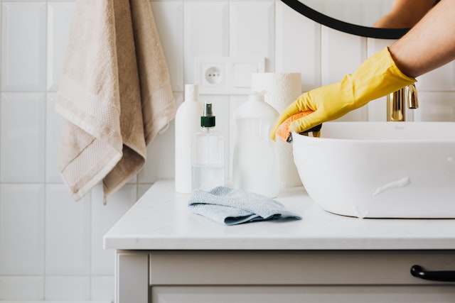 Person with yellow gloves cleaning sink