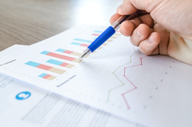 person looking at graphs with pen in hand