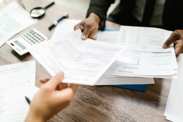 two people exchanging tax forms over a desk