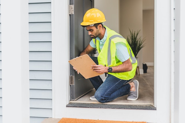 person in yellow vest inspecting doorframe